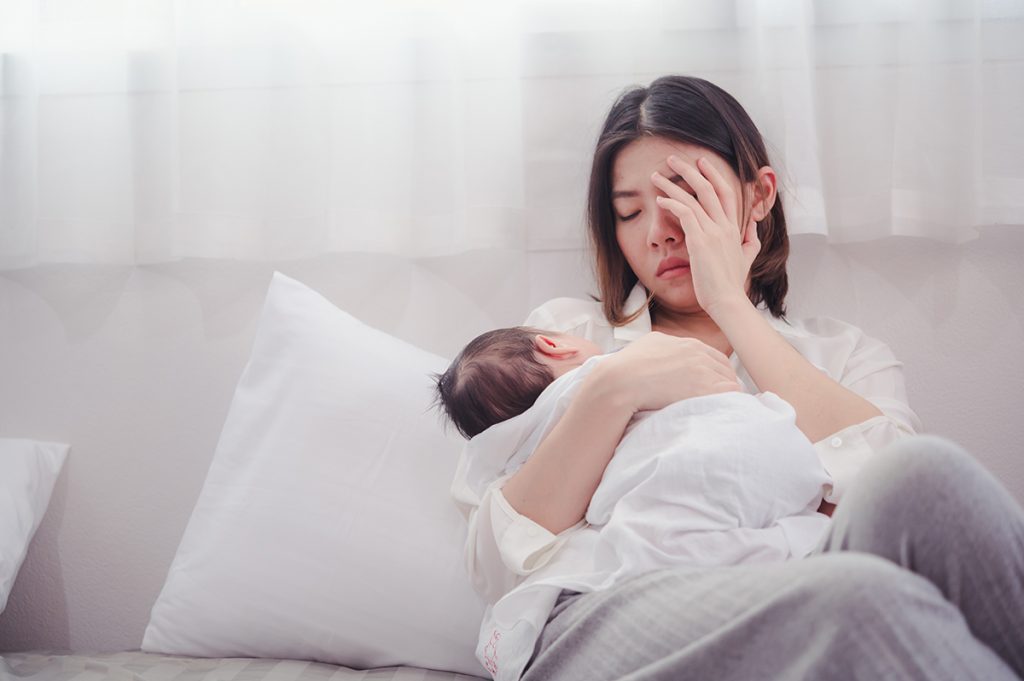 Tired new mother holding her baby, highlighting the need for Postpartum Treatment Chevy Chase for recovery and emotional support.