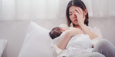 Tired new mother holding her baby, highlighting the need for Postpartum Treatment Chevy Chase for recovery and emotional support.